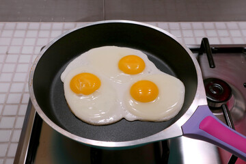 Closeup three of eggs being fried in a pan
