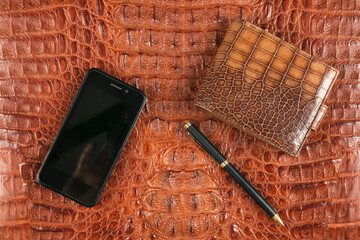Phone, wallet and pen lying on brown crocodile skin. Business - 436838249