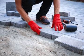 The master in yellow gloves lays paving stones