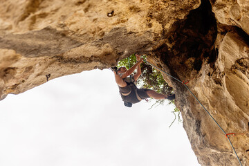 man climbing a stone arch in the mountain. risk sports and adventure. mountain activities.