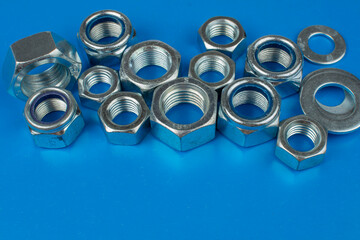 metal nuts and washers on blue background with copy space