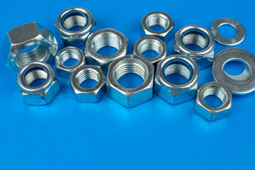 metal nuts and washers on blue background with copy space