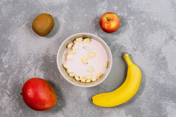 Fresh granola, muesli with coconut, banana and nuts in grey bowl on background.