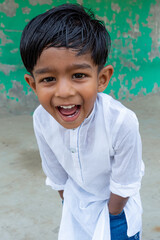 A white Punjabi-wearing two years kid is smiling and looking at the camera. 2-year kid face close-up views. A funny Asian boy is facing a camera.  