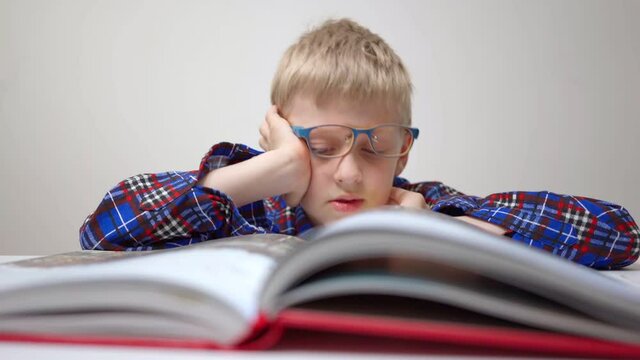 Schoolboy Reads Book And Falls Asleep Boy With Glasses Carefully Studies Book Back To School Homework. Preparing For Control Work. Grade School. School Student Teaches Lessons. Learn Remotely At Home 