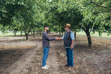 ranchers handshake in walnut orchard