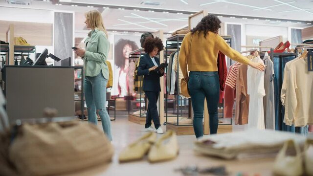 Customers Shopping in Modern Clothing Store, Retail Sales Associate Assists Client. Diverse People in Fashionable Shop, Choosing Stylish Clothes, Colorful Brand Designs, Quality Sustainable Materials.
