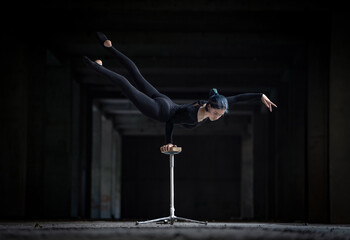 Female flexible circus artist doing handstand in abandoned tunnel. Concept of willpower, motivation and passion