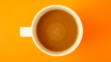 A full cup of coffee on a colored background. Coffee beans. Coffee foam.