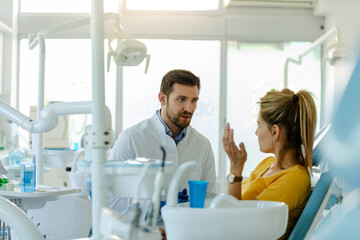 Male dentist in dental office talking with female patient and preparing her for treatment.