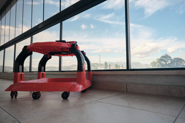 Colorful baby-walker on faience floor inside the huge balcony with cloudy sky background in glass...