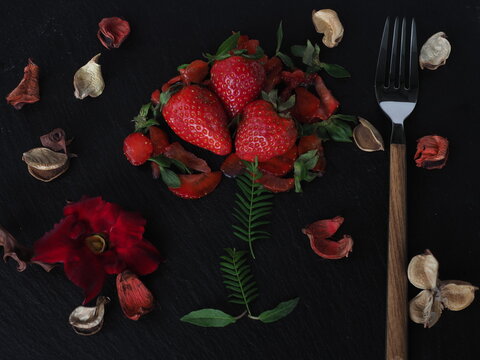 Strawberry plate on black slate decorated with dried flower and leaves