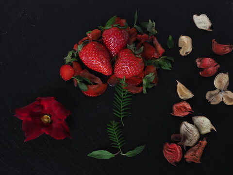 Ripe strawberries decorated with a red flower and dry leaves