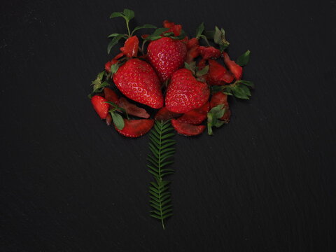 Grouped strawberries imitating a flower on a black plate