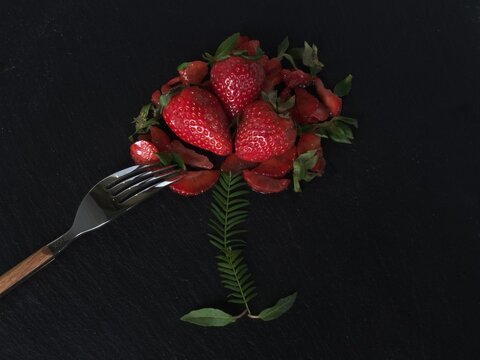 Strawberries grouped with a metal fork on the black plate