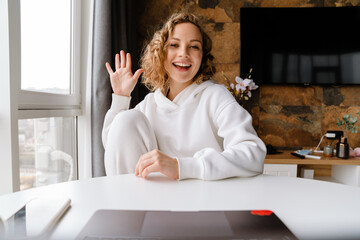 Fototapeta na wymiar White blonde woman gesturing and using laptop while sitting at table