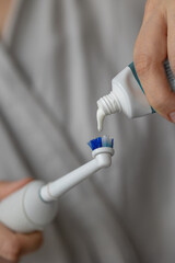 European woman brushing her teeth with an electric toothbrush, oral and dental care, human personal hygiene, toothpaste to strengthen and whiten teeth, fresh and healthy breath, taking care of health