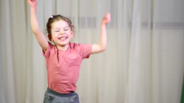 Happy child jumping and laughing. girl smiles and play at home. concept fun childhood. Funny girl dances and sings song. Waving his hands in room. family have enjoy activity together at home