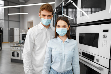 Fototapeta na wymiar Young couple wearing medical masks in hypermarket with home appliances