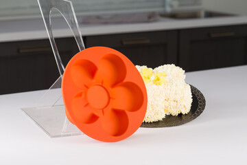 round orange silicone mold for baking, pastries or cakes, next to fruits and herbs, on a white...