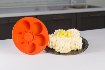 round orange silicone mold for baking, pastries or cakes, next to fruits and herbs, on a white...
