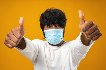 Positive handsome african american man with medical mask against yellow background