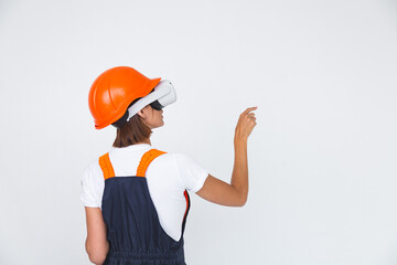 Pretty woman engineer in building protective helmet on white background in virtual reality glasses