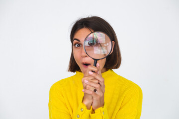 Pretty woman in yellow sweater on white background held magnifier happy positive playful