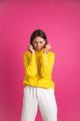 Beautiful woman in bright yellow sweater isolated on pink background stressful crying depression