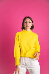 Obraz na płótnie Canvas Beautiful woman in bright yellow sweater white pants isolated on pink background posing positive emotions