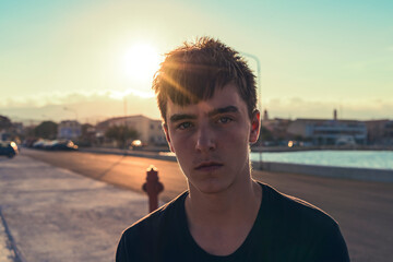 portrait of a serious teenager with the sun behind his head