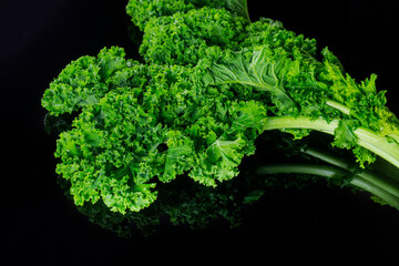Green kale leaves on black isolated background.