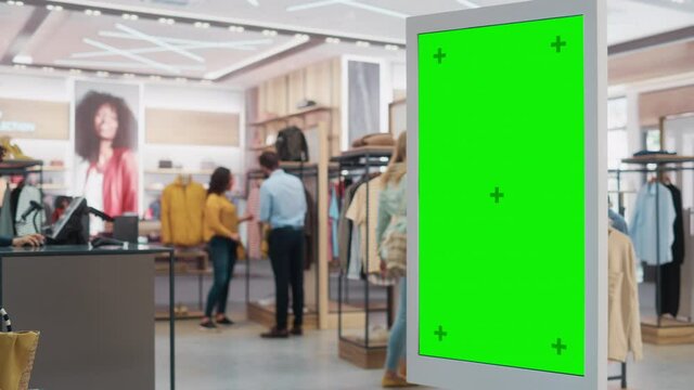 Customer Using Floor-Standing LCD Touch Display with Green Screen Chroma Key Mock Up while Shopping in Clothing Store. She is Checking for Information, Looking at a Floor Plan, Choosing Items Online.