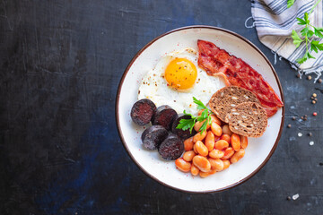 english breakfast fried egg fresh black pudding blood sausage, cereal bread, beans, bacon, scrambled eggs healthy meal snack copy space food background rustic 