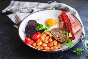 english breakfast fried egg fresh black pudding blood sausage, cereal bread, beans, bacon, scrambled eggs healthy meal snack copy space food background rustic 