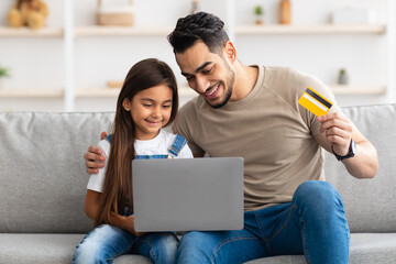 Happy family using computer and credit card at home