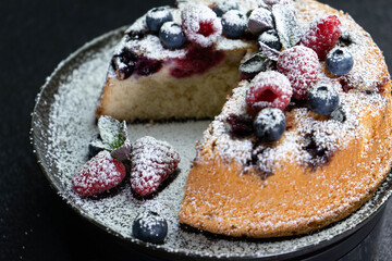 Fruit pie with powdered sugar and cinnamon on white plate, home baked closeup