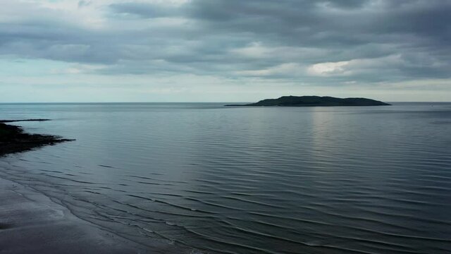 Cinematic aerial view over beach landscape and revealing the Irish sea and Lambay Island on a cloudy evening  Donabate beach in summer, Dublin, Ireland
