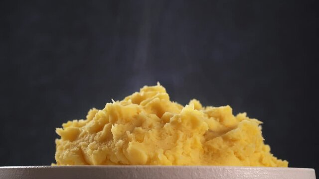 Mashed potatoes with steam on plate close up rotates