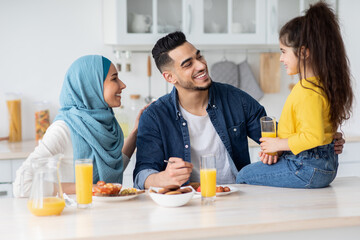 Obraz na płótnie Canvas Portrait Of Happy Muslim Family Of Three Eating Lunch In Kitchen Together