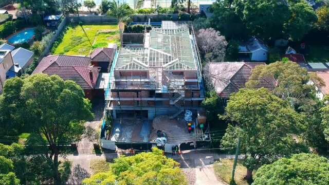 Aerial drone video of a brick house under construction with a flat timber roof truss visible Sydney NSW Australia