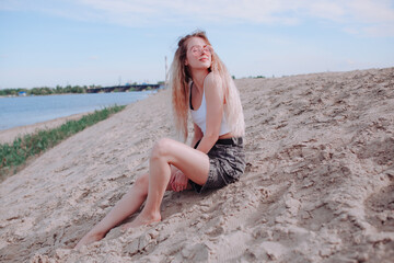 Fototapeta na wymiar a girl in shorts is sitting on the sand