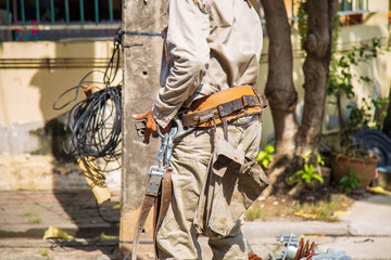 Electrical wireman wearing an old tool belt next to a light pole before repair a street light.