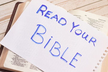 Read your Bible. Christian biblical concept. Handwritten note on opened Bible book with an...