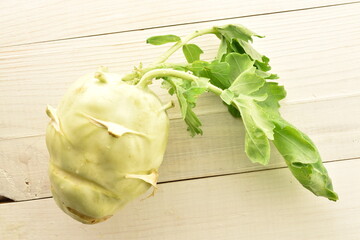 One organic kohlrabi cabbage on a wood table, close-up, top view.