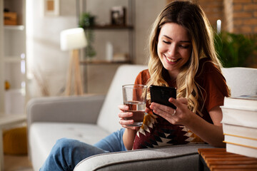  Girl holding a glass of water. Portrait of smiling girl typing a message