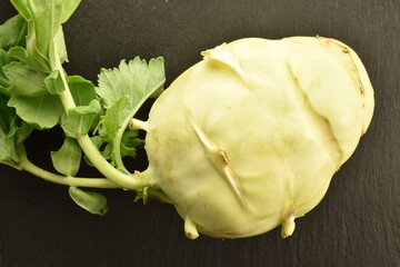 One kohlrabi cabbage on a slate board, close-up, top view.