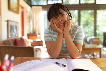 Obraz premium Asian girl wearing phone headset smiling during video call, learning online