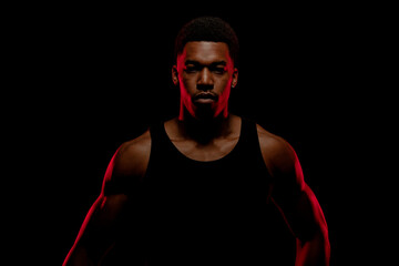 Basketball player with red side light against black background. Serious concentrated african american man. - Powered by Adobe