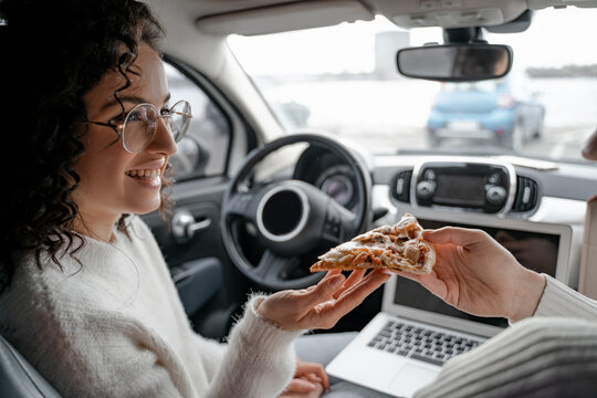 Man feeding girl a slice of pizza in automobile - Powered by Adobe
